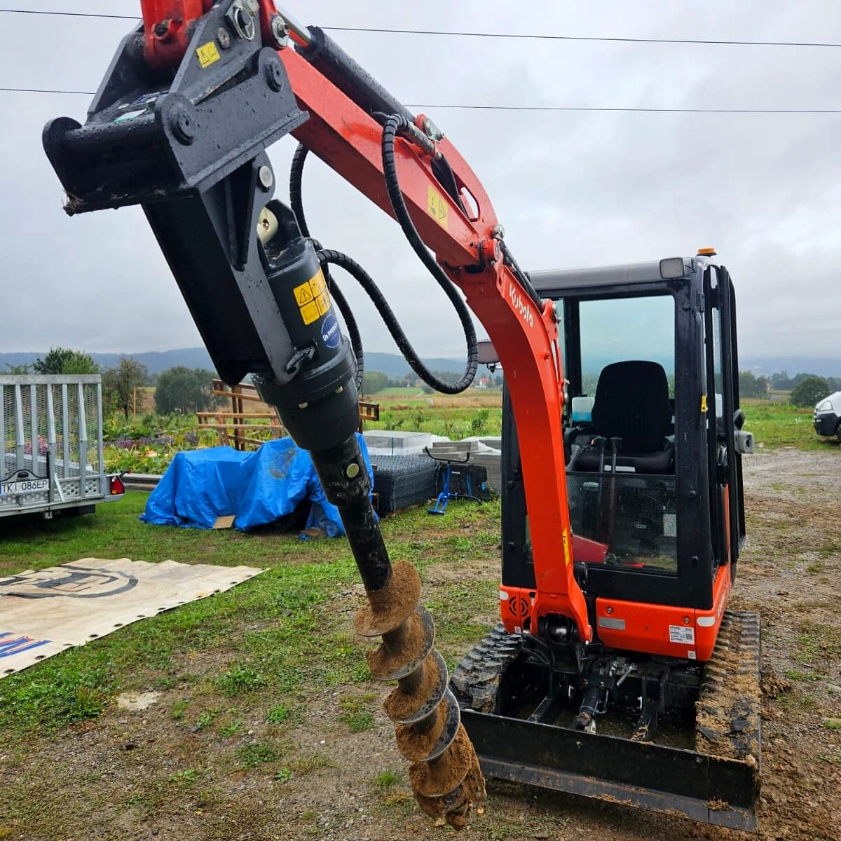 Earth auger fitted to a compact excavator